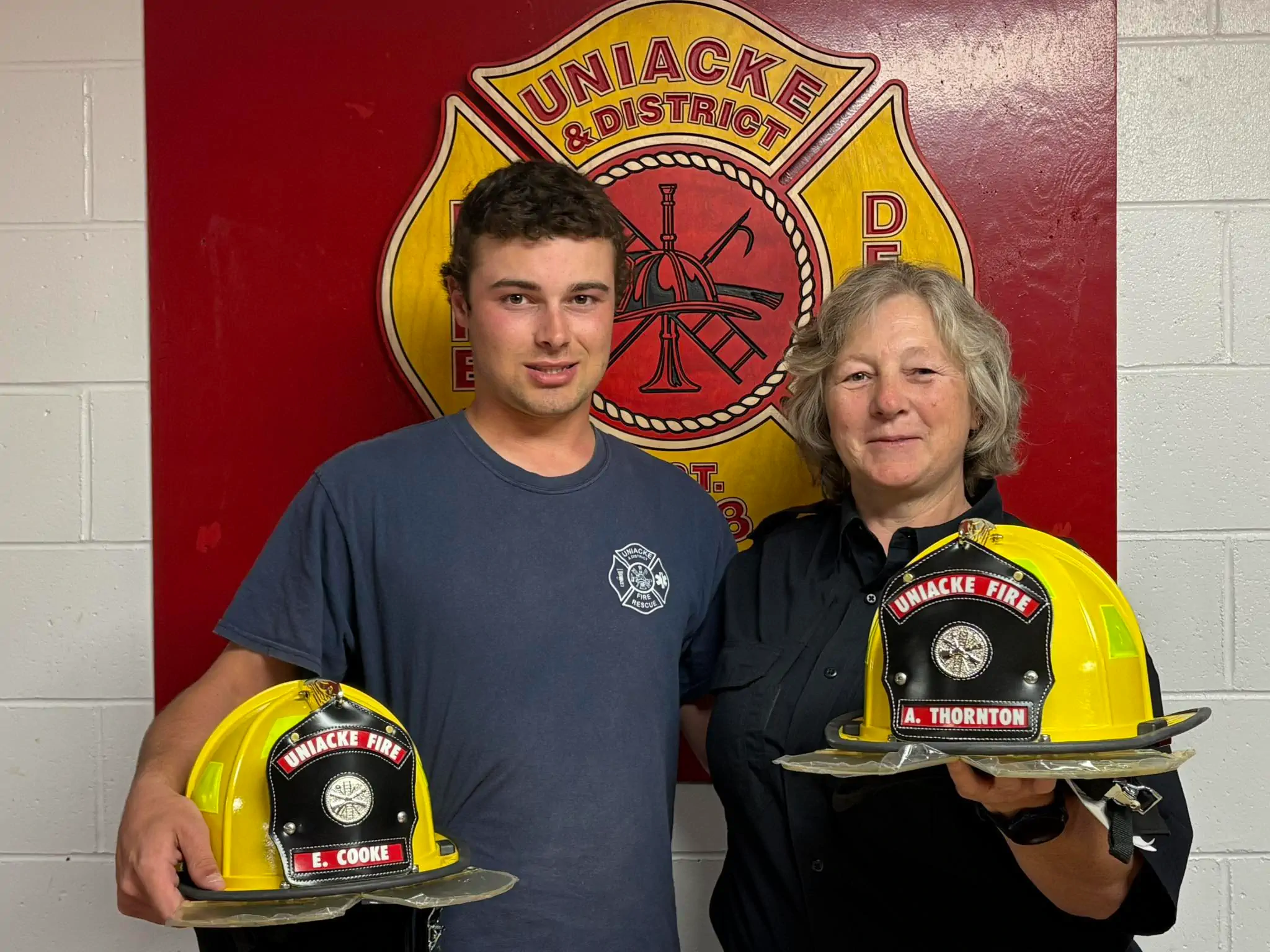 two firefighters holding helmets